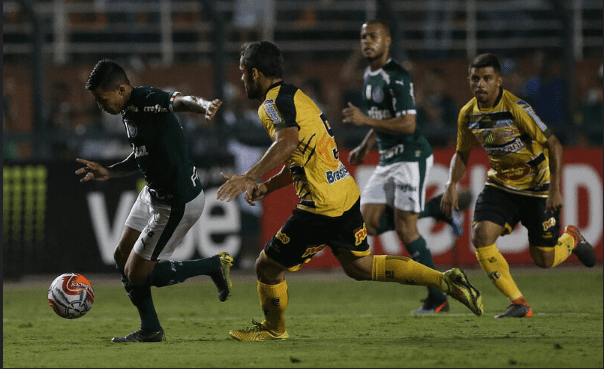 O jogador Dudu, da SE Palmeiras, disputa bola com o jogador Adilson, do G Novorizontino, durante partida valida pelas quartas de final (volta), do Campeonato Paulista, Série A1 2019, no Estádio do Pacaembu.