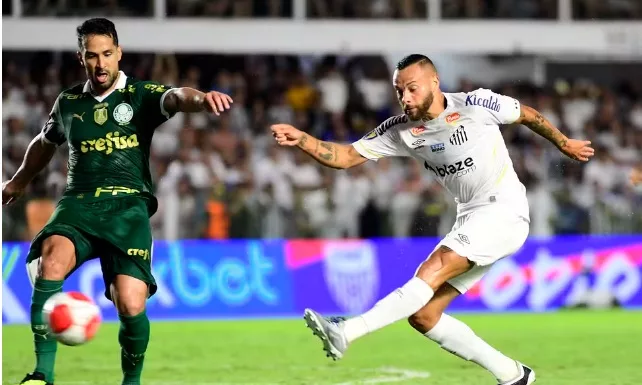 O jogador Luan, da SE Palmeiras, divide bola com Guilherme, do Santos, na partida de ida da final do Campeonato Paulista, na Vila Belmiro. (Foto: Marcos Ribolli)